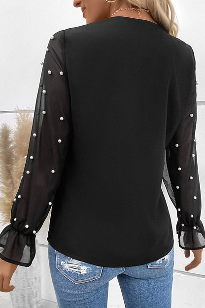 Blouse noire à col en V et manches volantées en maille perlée