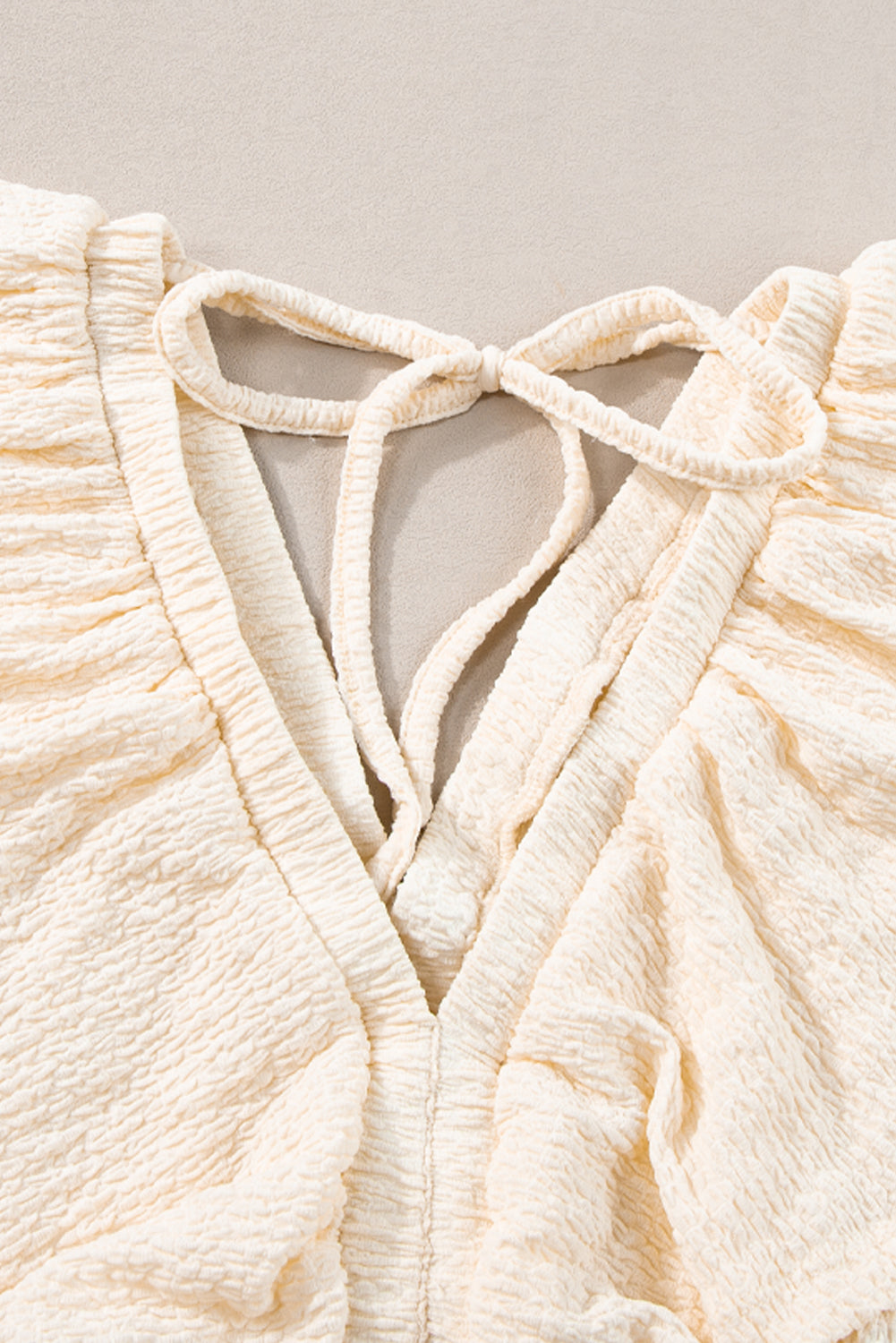 Mini-robe texturée beige à col en V profond et dos découpé